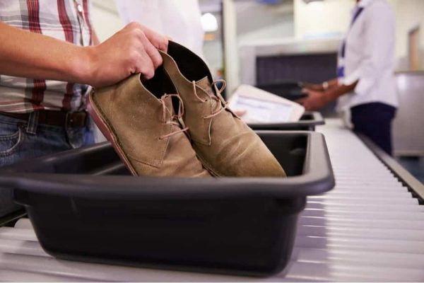 man-putting-shoes-into-tray-airport-min